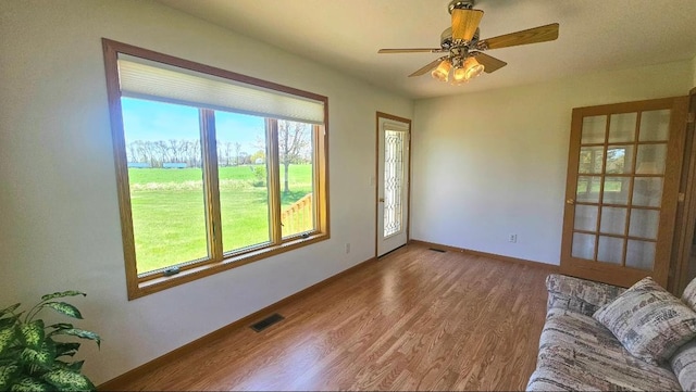 unfurnished living room with wood finished floors, a ceiling fan, and baseboards