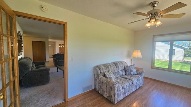 living area with wood finished floors, baseboards, and a ceiling fan