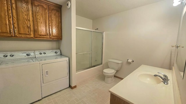 bathroom featuring washing machine and dryer, toilet, baseboards, combined bath / shower with glass door, and vanity