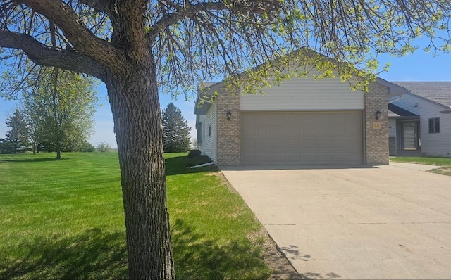 view of home's exterior with brick siding, an attached garage, a lawn, and driveway