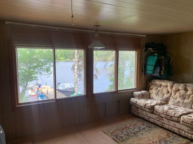 living area featuring a water view, wooden walls, and wood ceiling