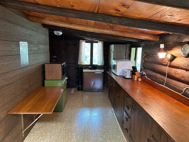 interior space featuring beamed ceiling, wooden walls, rustic walls, and wooden ceiling