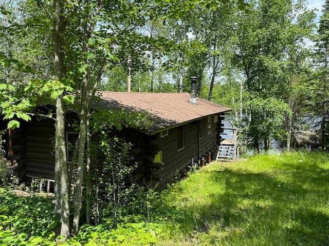 view of side of property with a shingled roof and log exterior
