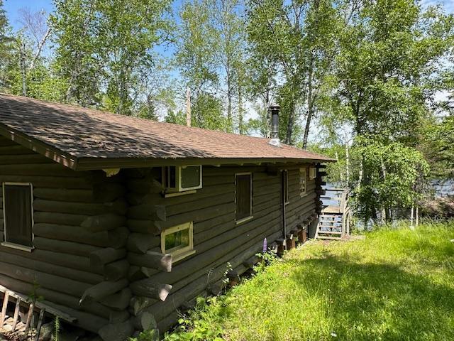 view of side of home with a shingled roof and log exterior
