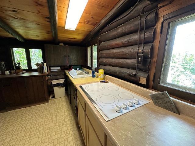 kitchen with wooden ceiling, vaulted ceiling, rustic walls, and white electric cooktop
