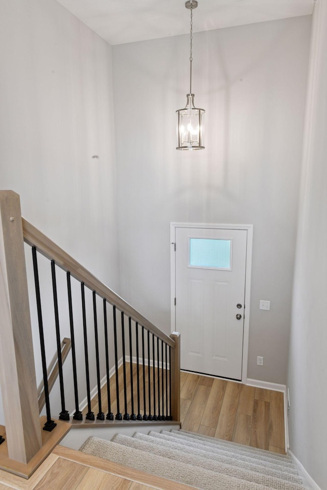 entryway featuring a chandelier, wood finished floors, stairway, and baseboards