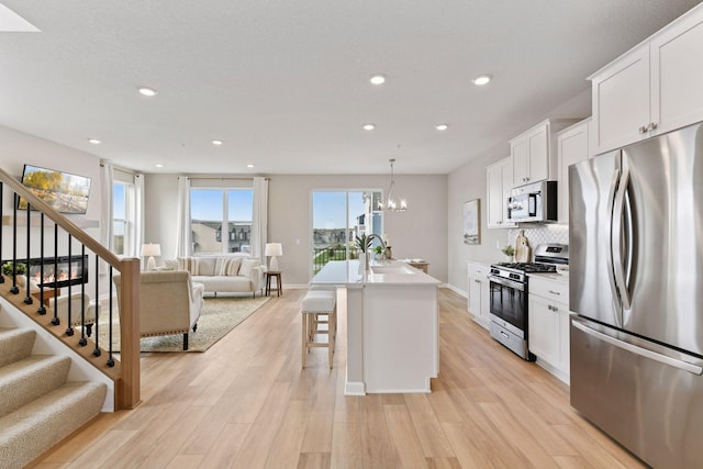 kitchen featuring stainless steel appliances, open floor plan, a sink, light wood-type flooring, and recessed lighting