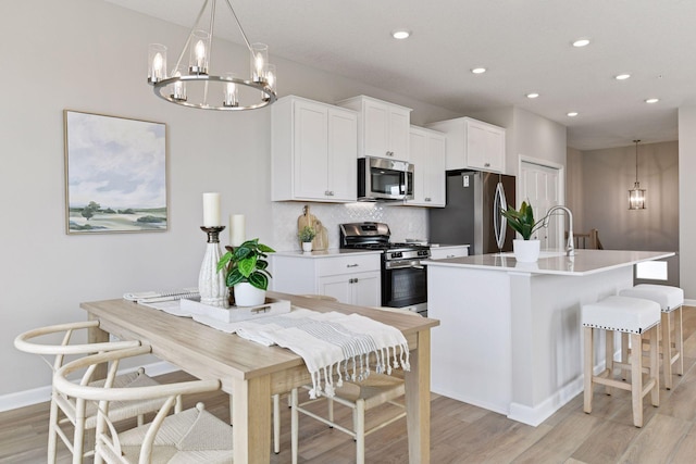 kitchen featuring stainless steel appliances, a chandelier, light wood-type flooring, recessed lighting, and baseboards