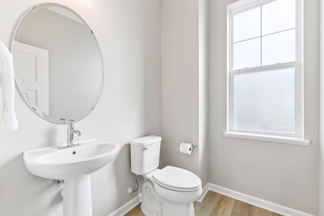 bathroom featuring baseboards, toilet, wood finished floors, and plenty of natural light