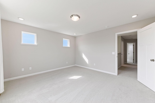spare room featuring light colored carpet, healthy amount of natural light, baseboards, and recessed lighting