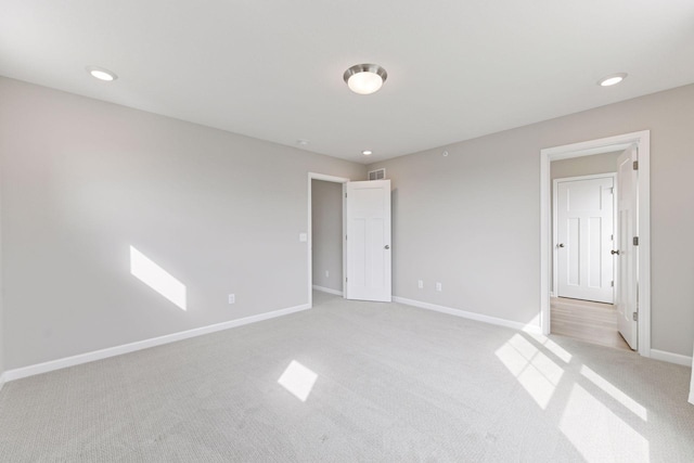 unfurnished bedroom featuring light carpet, baseboards, and recessed lighting