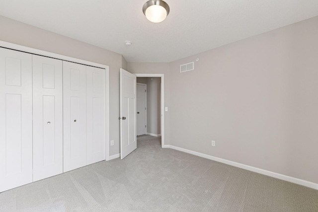 unfurnished bedroom featuring light carpet, baseboards, and a closet