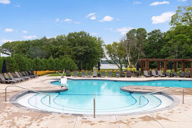 community pool featuring a patio area, a pergola, and view of wooded area