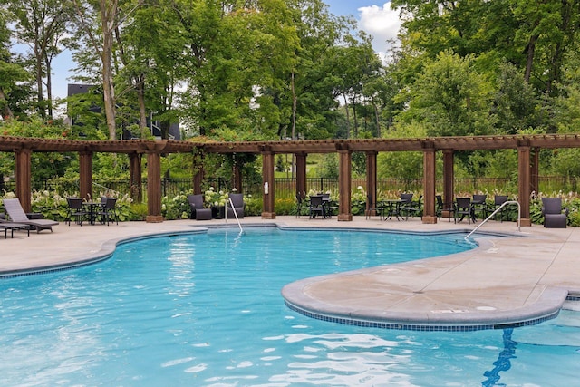 community pool with fence, a patio, and view of wooded area