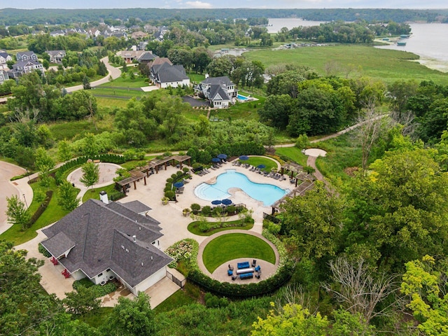aerial view of property's location featuring a large body of water, a pool area, and a tree filled landscape