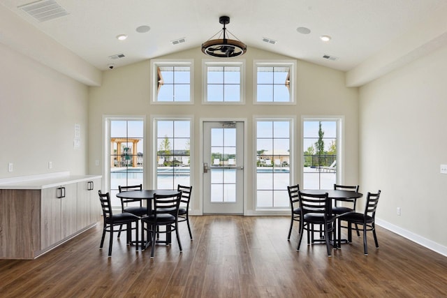 dining room with dark wood-style floors, plenty of natural light, high vaulted ceiling, and baseboards