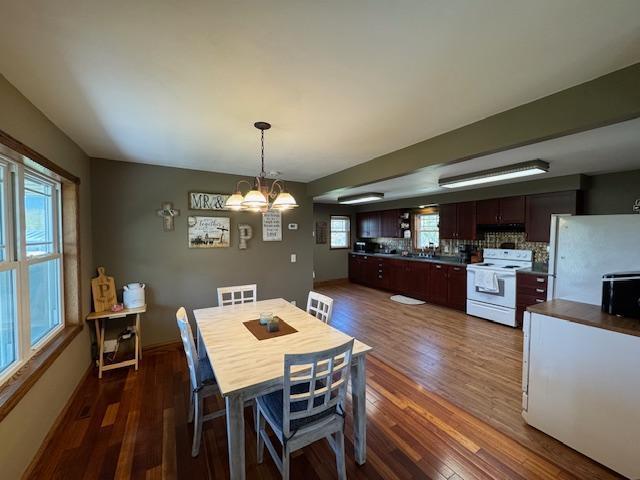 dining area with dark wood-style floors, a chandelier, and healthy amount of natural light