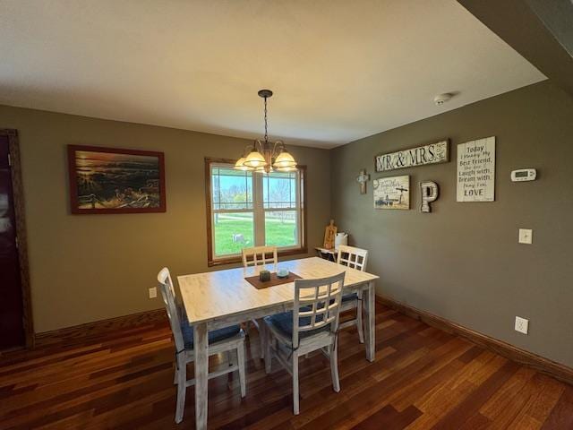 dining room with a chandelier, dark wood finished floors, and baseboards