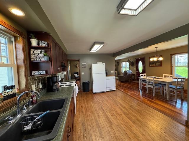 kitchen with freestanding refrigerator, a sink, light wood-type flooring, a chandelier, and open shelves
