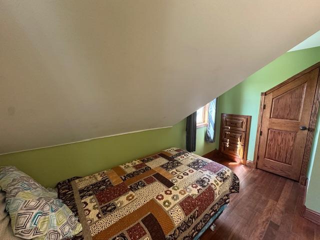 bedroom featuring dark wood finished floors and lofted ceiling