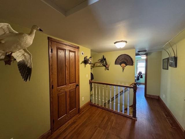 hall featuring an upstairs landing, wood finished floors, and baseboards