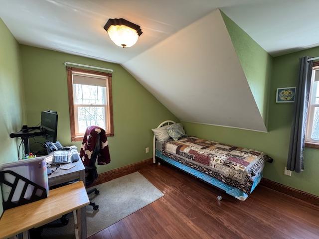 bedroom featuring wood finished floors, a desk, baseboards, and vaulted ceiling