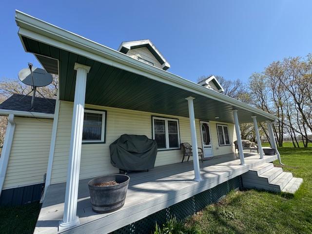 back of property with covered porch and a yard