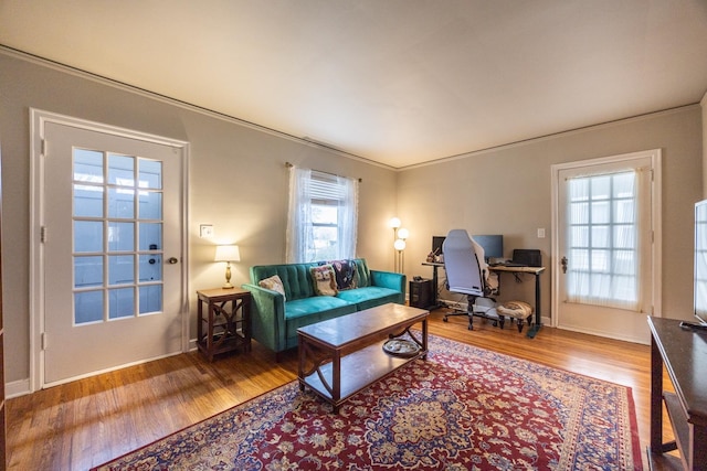 living room featuring wood finished floors, an office area, crown molding, and baseboards