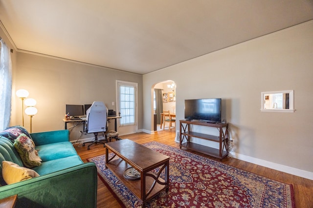 living area featuring arched walkways, baseboards, wood finished floors, and a desk