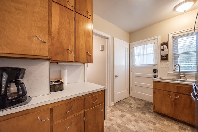 kitchen with a sink, light countertops, and brown cabinets