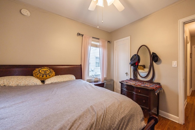 bedroom with crown molding, wood finished floors, baseboards, and ceiling fan