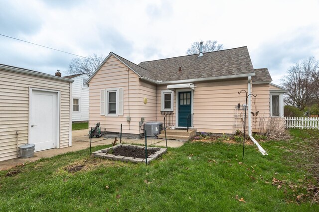 rear view of house with central air condition unit and roof with shingles