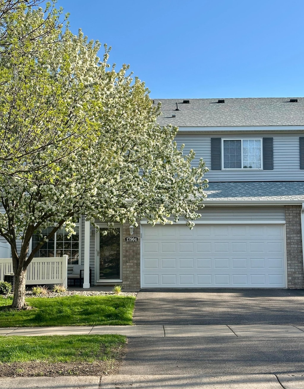 view of front of house featuring an attached garage, a shingled roof, brick siding, and driveway