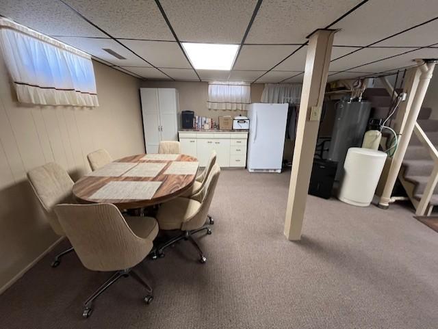 dining room featuring gas water heater, carpet flooring, visible vents, and a drop ceiling