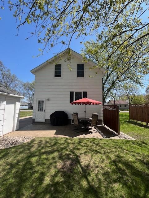 rear view of property with a yard, a patio, and fence