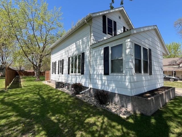 view of side of property featuring a lawn and fence