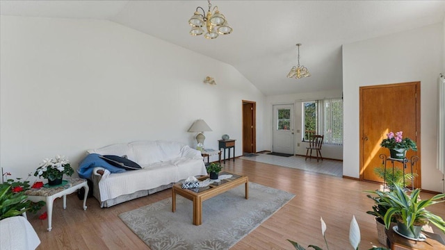 living room featuring vaulted ceiling, a chandelier, and wood finished floors