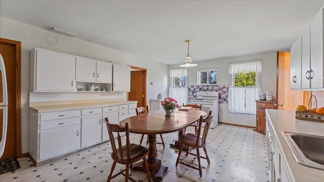 kitchen featuring electric range, light floors, white cabinets, and light countertops