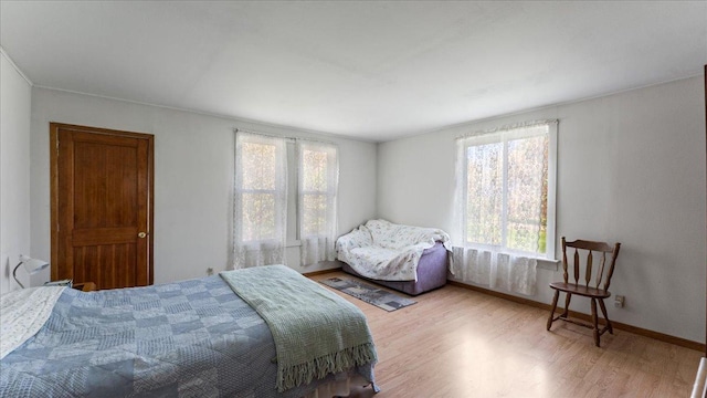 bedroom with wood finished floors, multiple windows, and baseboards