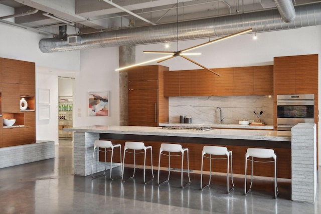 700 2nd St Unit W31, Minneapolis, MN 55401 - kitchen featuring stainless steel appliances, brown cabinetry, a kitchen breakfast bar, modern cabinets, and a towering ceiling
