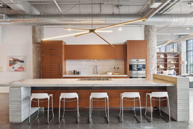 700 2nd St Unit W31, Minneapolis, MN 55401 - kitchen featuring finished concrete flooring, a breakfast bar, stainless steel appliances, brown cabinetry, and light stone countertops