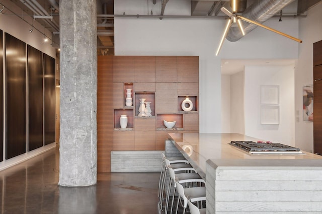 700 2nd St Unit W31, Minneapolis, MN 55401 - kitchen with stainless steel gas stovetop, a kitchen bar, light countertops, a high ceiling, and concrete floors