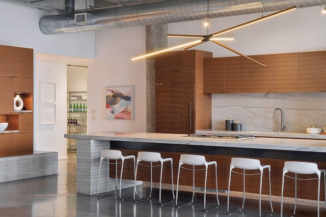 700 2nd St Unit W31, Minneapolis, MN 55401 - kitchen with a breakfast bar area, brown cabinetry, modern cabinets, backsplash, and a high ceiling