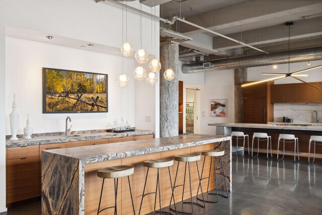 700 2nd St Unit W31, Minneapolis, MN 55401 - kitchen with brown cabinetry, visible vents, a kitchen bar, a towering ceiling, and concrete flooring