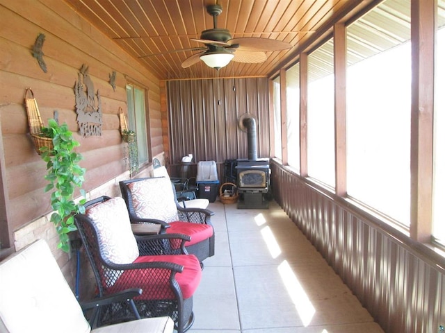 sunroom with ceiling fan and a wood stove