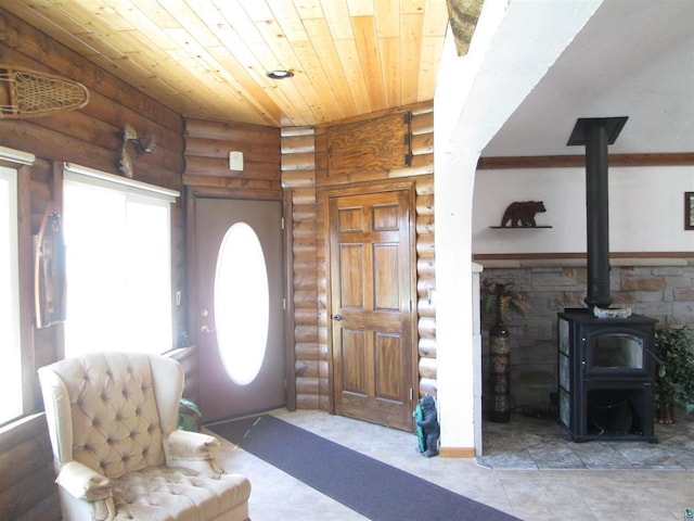 tiled entryway featuring a wood stove, wood ceiling, and rustic walls
