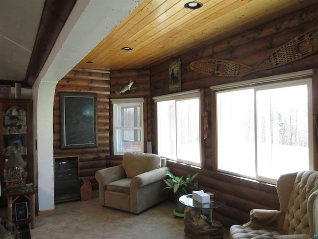 living room featuring carpet flooring, rustic walls, and beverage cooler