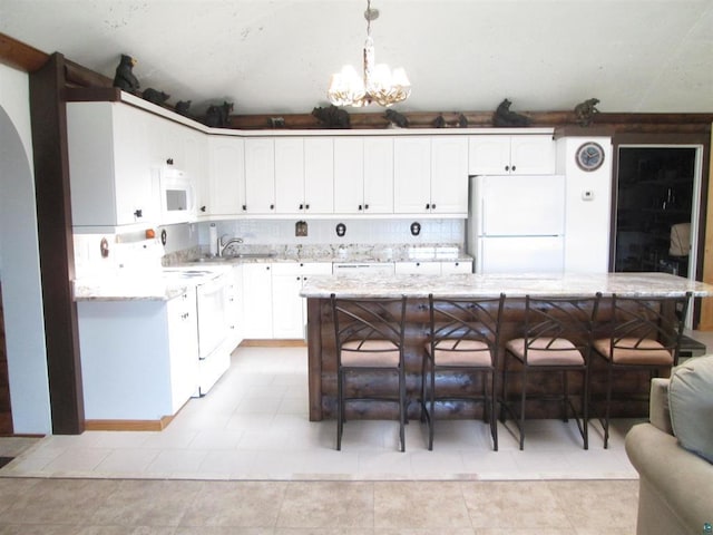 kitchen featuring white cabinets, light stone countertops, a sink, and white appliances