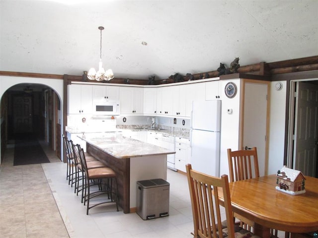 kitchen with a kitchen island, white cabinetry, arched walkways, white appliances, and a chandelier