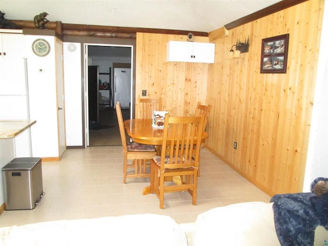 dining area with light tile patterned floors, wooden walls, and baseboards